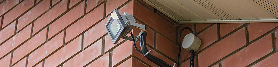 Прожектор, установленный под крышей на фасаде дома