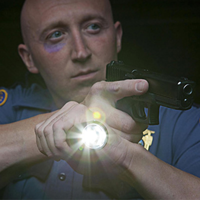 Полицейский с фингалом и фонарем в руках - фото
